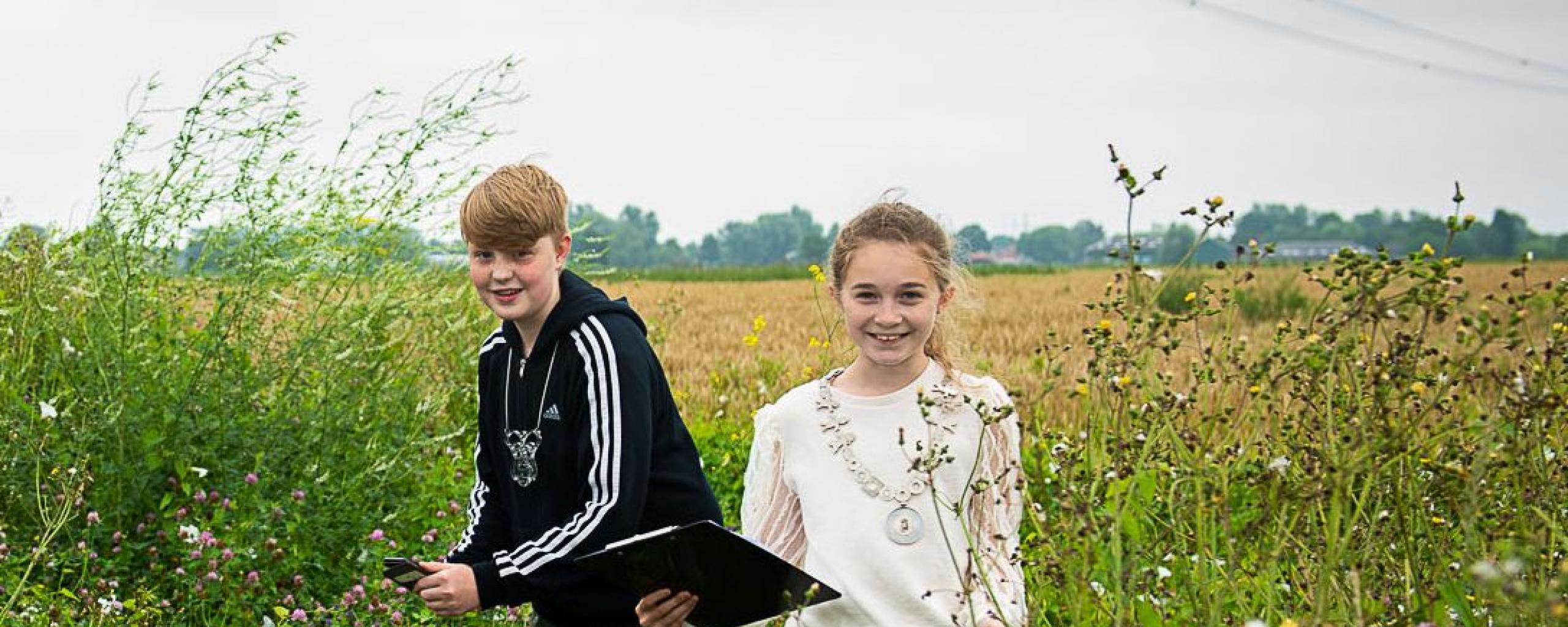 Kinderburgemeesters Robin en Eva in een bloemrijke akkerrand